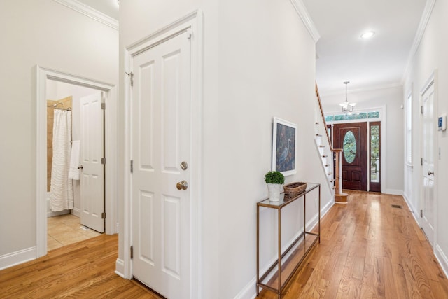 foyer with light hardwood / wood-style floors, a notable chandelier, and ornamental molding