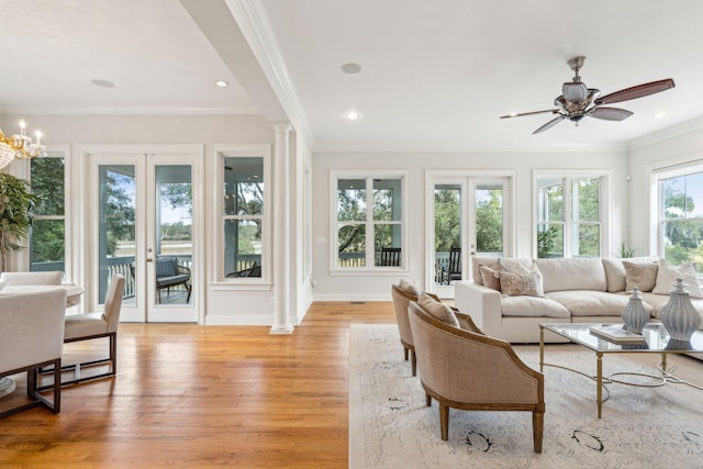 sunroom with ceiling fan with notable chandelier and decorative columns