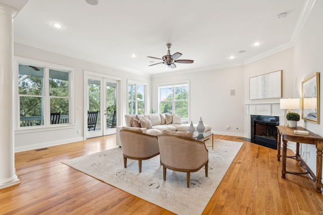 living room with ornate columns, light hardwood / wood-style floors, and crown molding