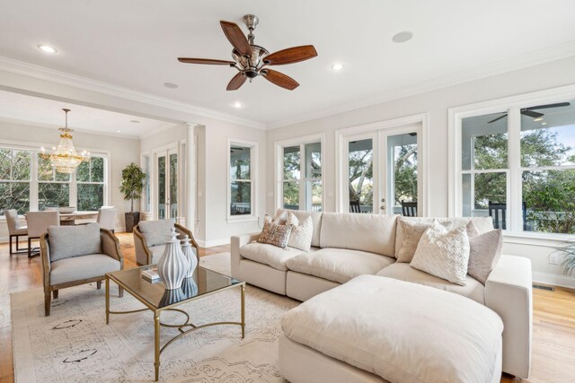 living room with ornamental molding, light hardwood / wood-style floors, and ceiling fan with notable chandelier