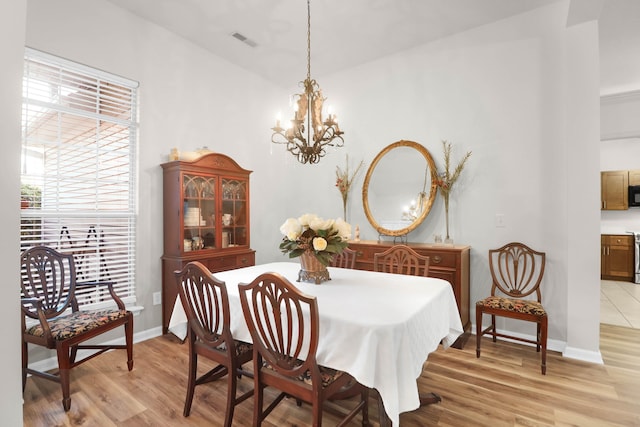 dining room with an inviting chandelier, light wood-style floors, visible vents, and baseboards