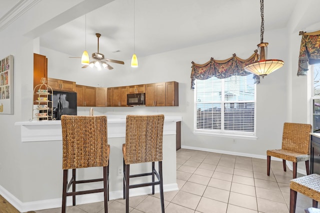 kitchen featuring pendant lighting, light countertops, brown cabinets, black appliances, and a ceiling fan