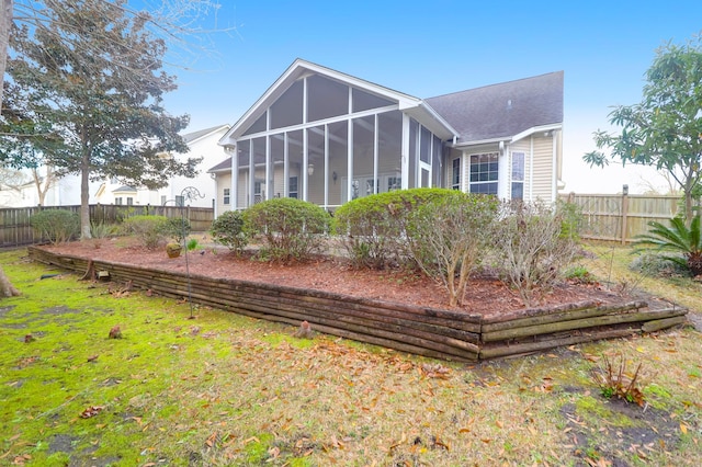 rear view of house with a yard, fence, and a sunroom