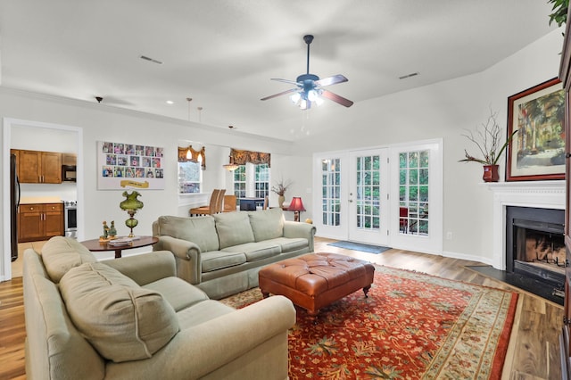 living room with baseboards, visible vents, a fireplace with flush hearth, ceiling fan, and light wood-type flooring