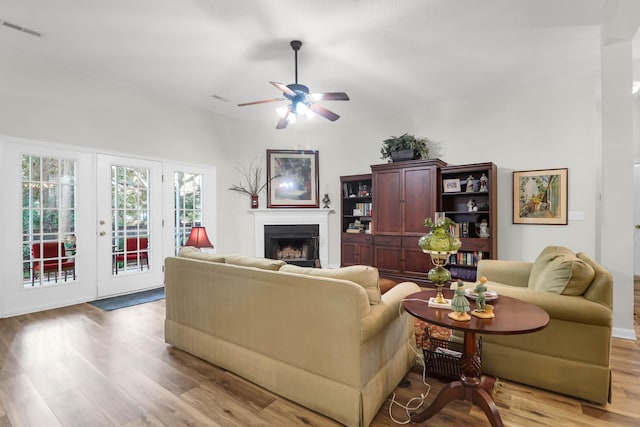 living area featuring a ceiling fan, wood finished floors, a fireplace, and visible vents