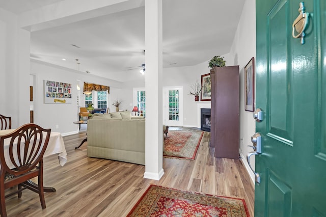 foyer featuring a ceiling fan, a fireplace, light wood-type flooring, and baseboards