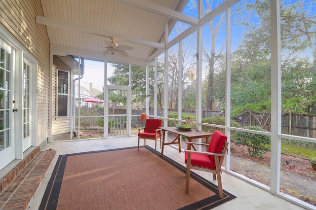 sunroom with lofted ceiling with beams and a ceiling fan