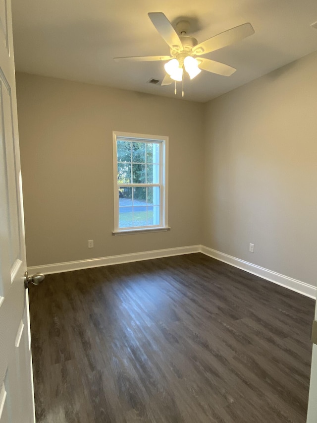 spare room featuring dark wood-type flooring, visible vents, ceiling fan, and baseboards