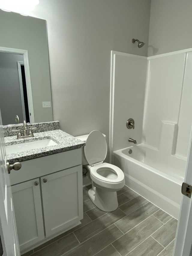 bathroom featuring toilet, vanity, wood finish floors, and bathing tub / shower combination