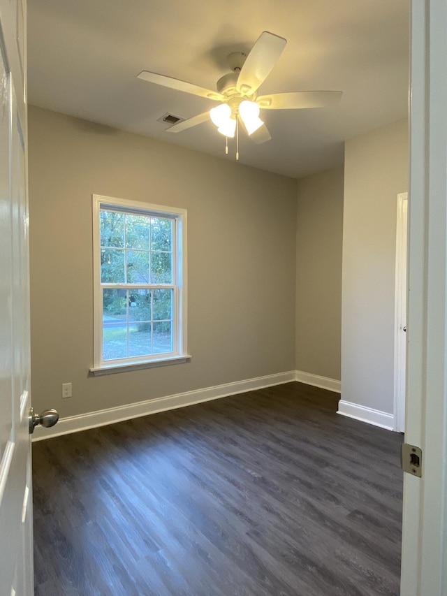 empty room featuring dark wood-style floors, visible vents, baseboards, and a ceiling fan