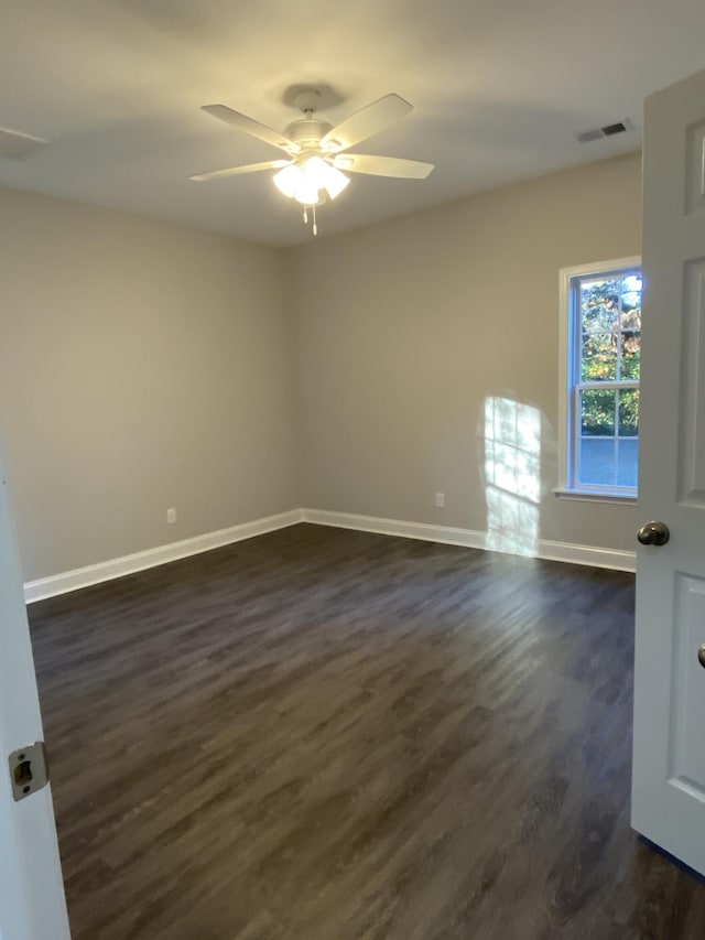 empty room with baseboards, visible vents, dark wood finished floors, and a ceiling fan