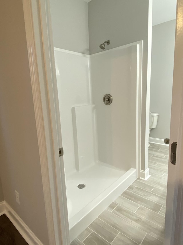 bathroom with a shower stall, baseboards, and wood finish floors