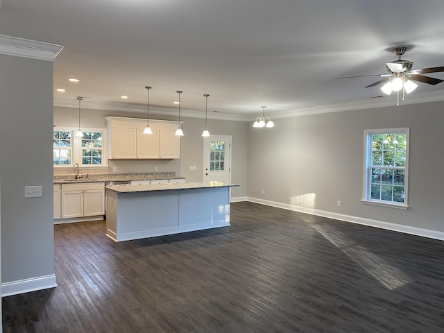 kitchen with a kitchen island, a sink, a wealth of natural light, and baseboards