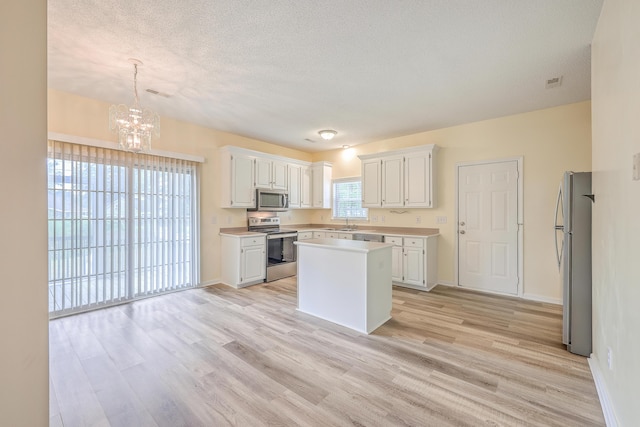 kitchen featuring appliances with stainless steel finishes, light countertops, white cabinets, and light wood-style flooring