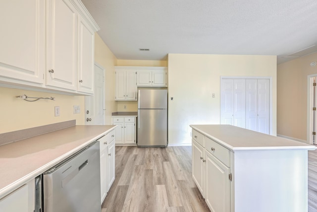 kitchen featuring white cabinets, light wood-style flooring, appliances with stainless steel finishes, a center island, and light countertops