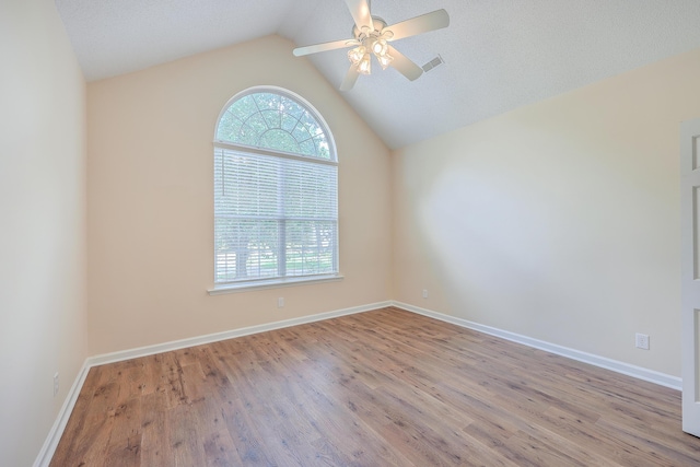 empty room featuring visible vents, vaulted ceiling, ceiling fan, wood finished floors, and baseboards