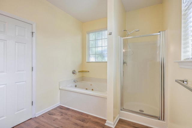 bathroom with a whirlpool tub, wood finished floors, a shower stall, and baseboards