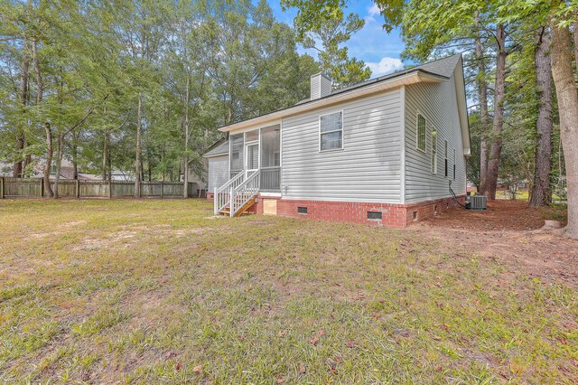 back of house featuring a sunroom, crawl space, fence, a yard, and central AC