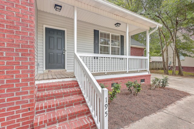 entrance to property featuring a porch, crawl space, and brick siding