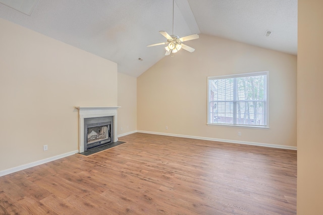 unfurnished living room with a fireplace with flush hearth, vaulted ceiling, ceiling fan, wood finished floors, and baseboards