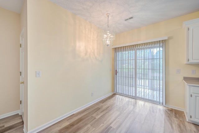unfurnished dining area featuring light wood-type flooring, visible vents, and baseboards