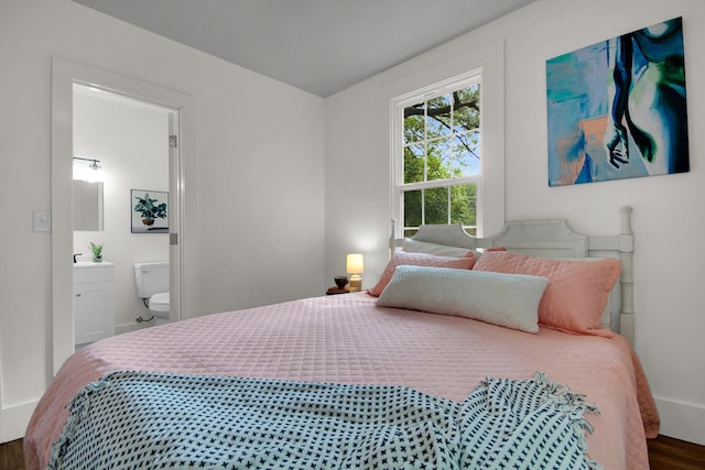 bedroom with ensuite bath and dark wood-type flooring