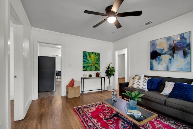 living room featuring ceiling fan, ornamental molding, and dark wood-type flooring