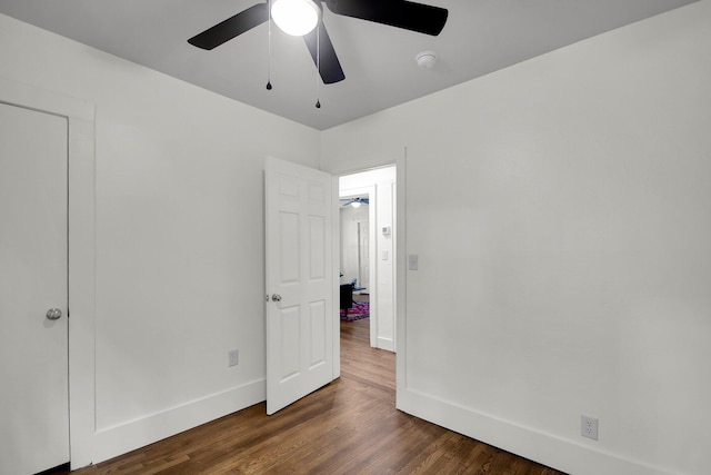 unfurnished bedroom with ceiling fan and dark wood-type flooring