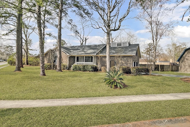 view of front of house featuring a porch, brick siding, fence, and a front lawn