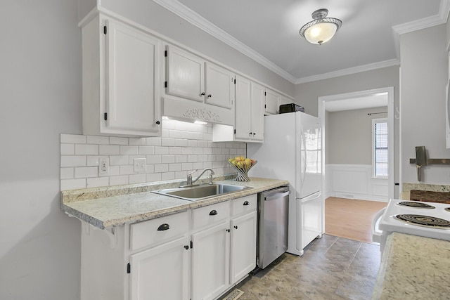 kitchen featuring a wainscoted wall, white appliances, a sink, white cabinets, and ornamental molding