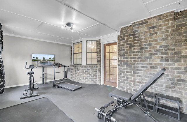 exercise area with brick wall and baseboards