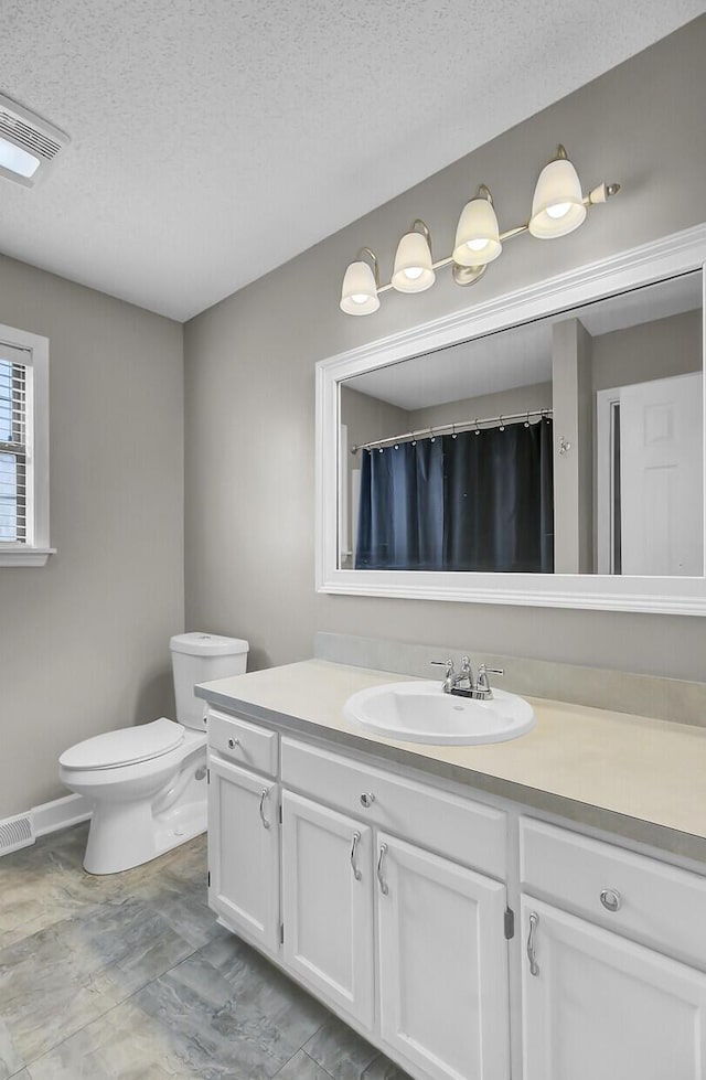 bathroom with visible vents, vanity, toilet, and a textured ceiling