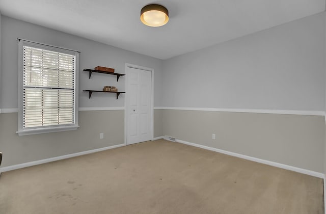 unfurnished room with carpet, visible vents, and baseboards