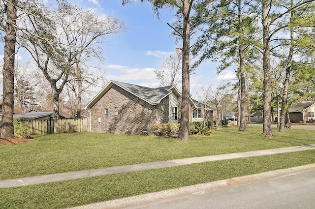 view of side of home with fence, a lawn, and brick siding