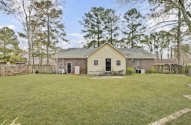 rear view of property featuring entry steps, a yard, brick siding, and a fenced backyard