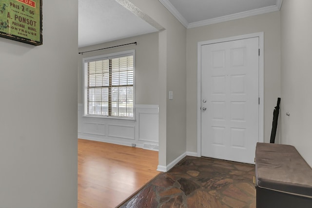 entrance foyer with baseboards, a wainscoted wall, wood finished floors, crown molding, and a decorative wall