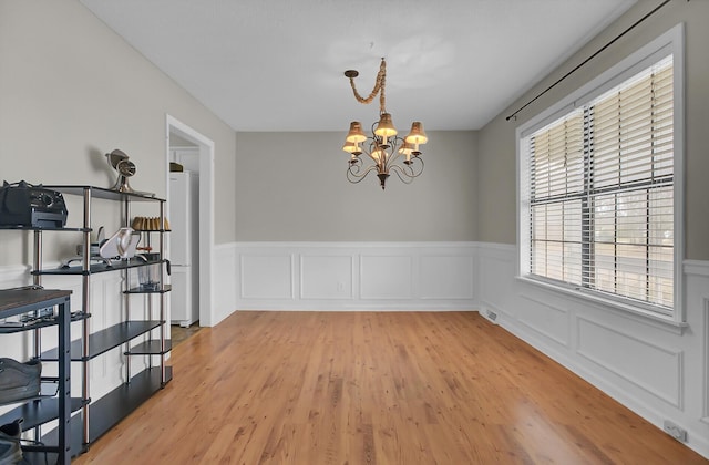 dining area with light wood-style floors, visible vents, a chandelier, and a wainscoted wall