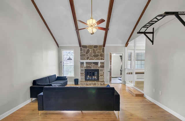 living area featuring vaulted ceiling with beams, wood finished floors, and a stone fireplace