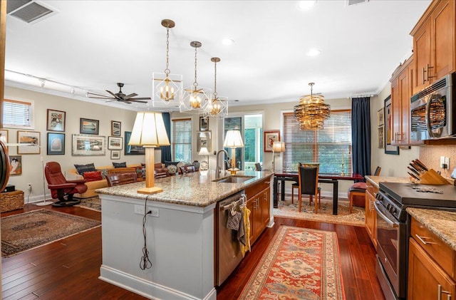 kitchen with appliances with stainless steel finishes, sink, ornamental molding, dark hardwood / wood-style floors, and a kitchen island with sink