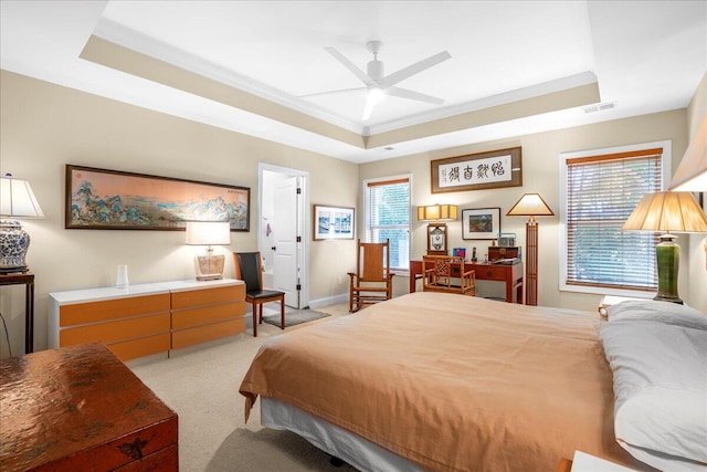 bedroom with light carpet, multiple windows, and a raised ceiling