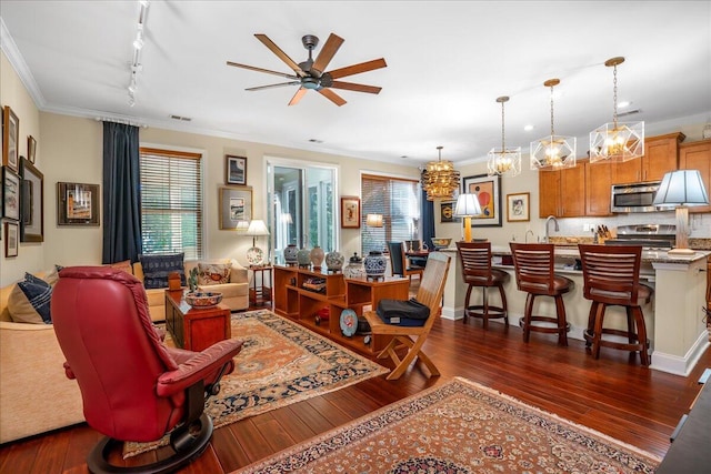 living room featuring crown molding, ceiling fan with notable chandelier, rail lighting, and dark hardwood / wood-style flooring