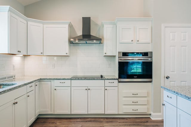 kitchen with white cabinetry, wall chimney range hood, oven, and black electric stovetop