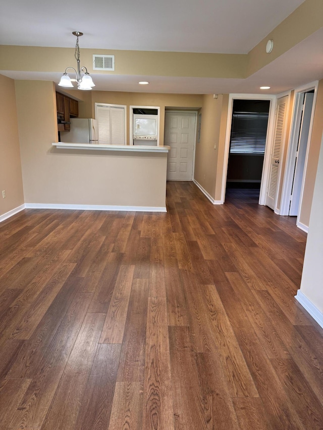 unfurnished living room with a notable chandelier and dark hardwood / wood-style floors