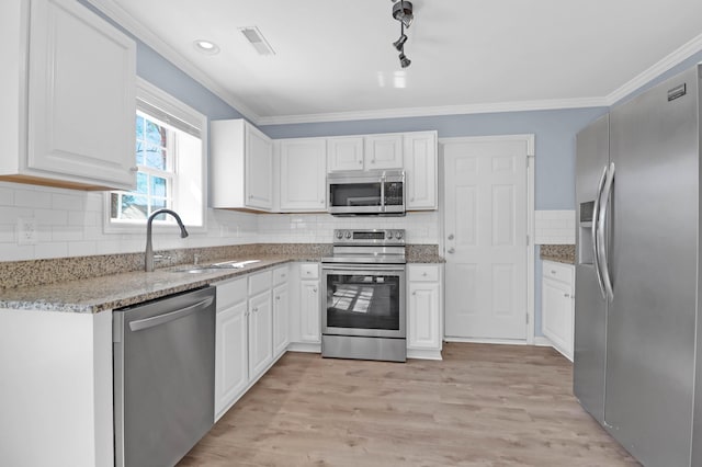 kitchen featuring light wood finished floors, a sink, ornamental molding, stainless steel appliances, and white cabinetry