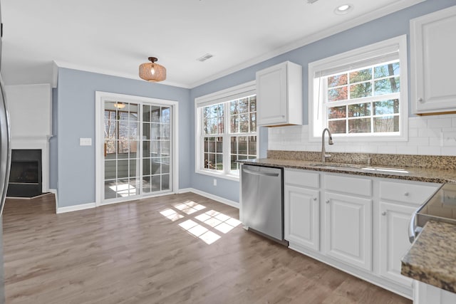 kitchen with backsplash, white cabinets, ornamental molding, and stainless steel dishwasher