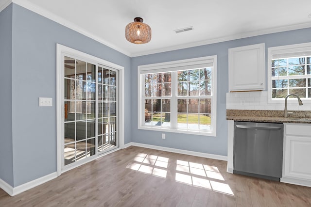 unfurnished dining area with crown molding, light wood-style floors, visible vents, and baseboards