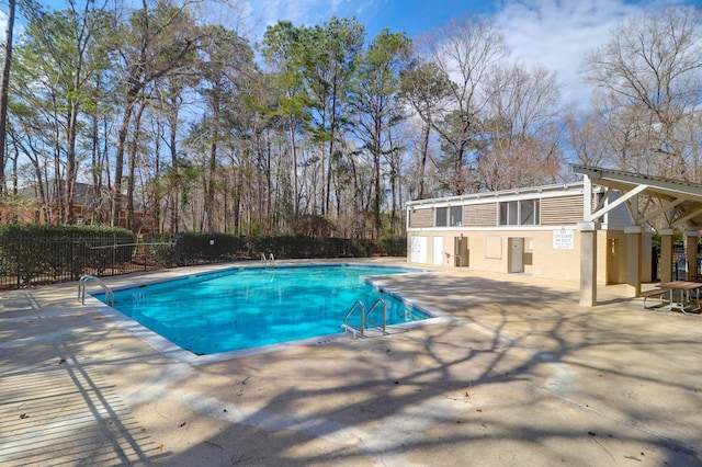 community pool with a patio and fence