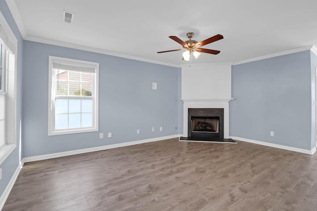 unfurnished living room with wood finished floors, a fireplace with raised hearth, and crown molding