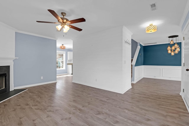 unfurnished living room with crown molding, wood finished floors, and a fireplace with raised hearth