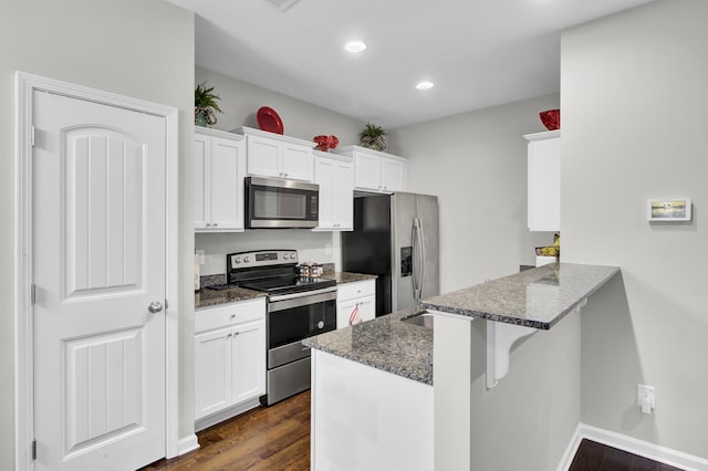 kitchen featuring white cabinets, kitchen peninsula, stainless steel appliances, and a kitchen bar